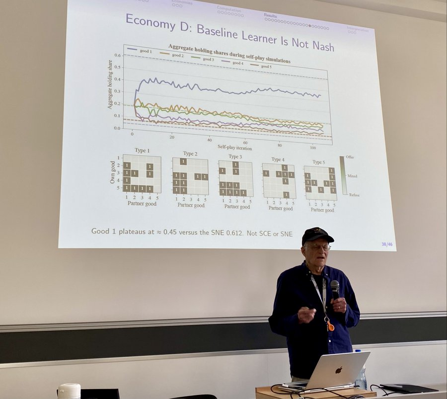 Tom Sargent (NYU) presented “How Should I Trade?” (with Ziyue Yang). Reinforcement learning meets Kiyotaki–Wright: can monetary exchange emerge when agents do not know the distribution and learn only from bilateral experience with MuZero?